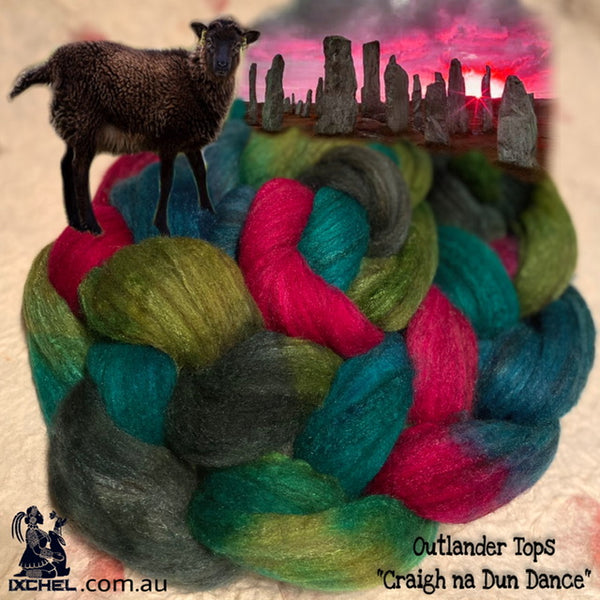 A colorful blend of fiber roving in shades of green, pink, blue, and brown, with a small model of a sheep on top, against a backdrop of Celtic Stones at sunset.