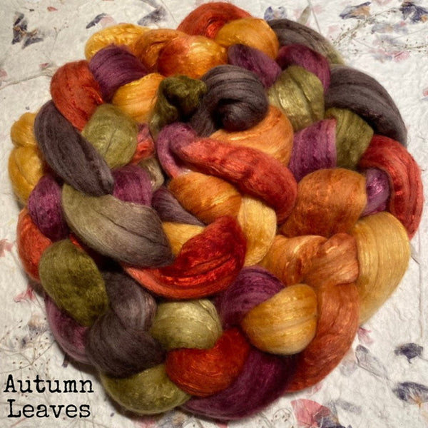 A braid of fluffy, soft, multi-coloured hand dyed IxCHeL cashmerino silk top  roving with autumn leaf colours including orange, red, purple, yellow, and olive green, labeled 'Autumn Leaves'.