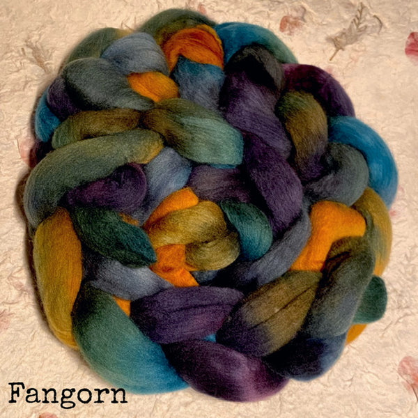 A braid of IxCHeL handdyed roving Polwarth top with teal, purple, blue, olive green, and orange, photographed on a handmade paper  background. The word 'Fangorn' appears in the lower-left corner.